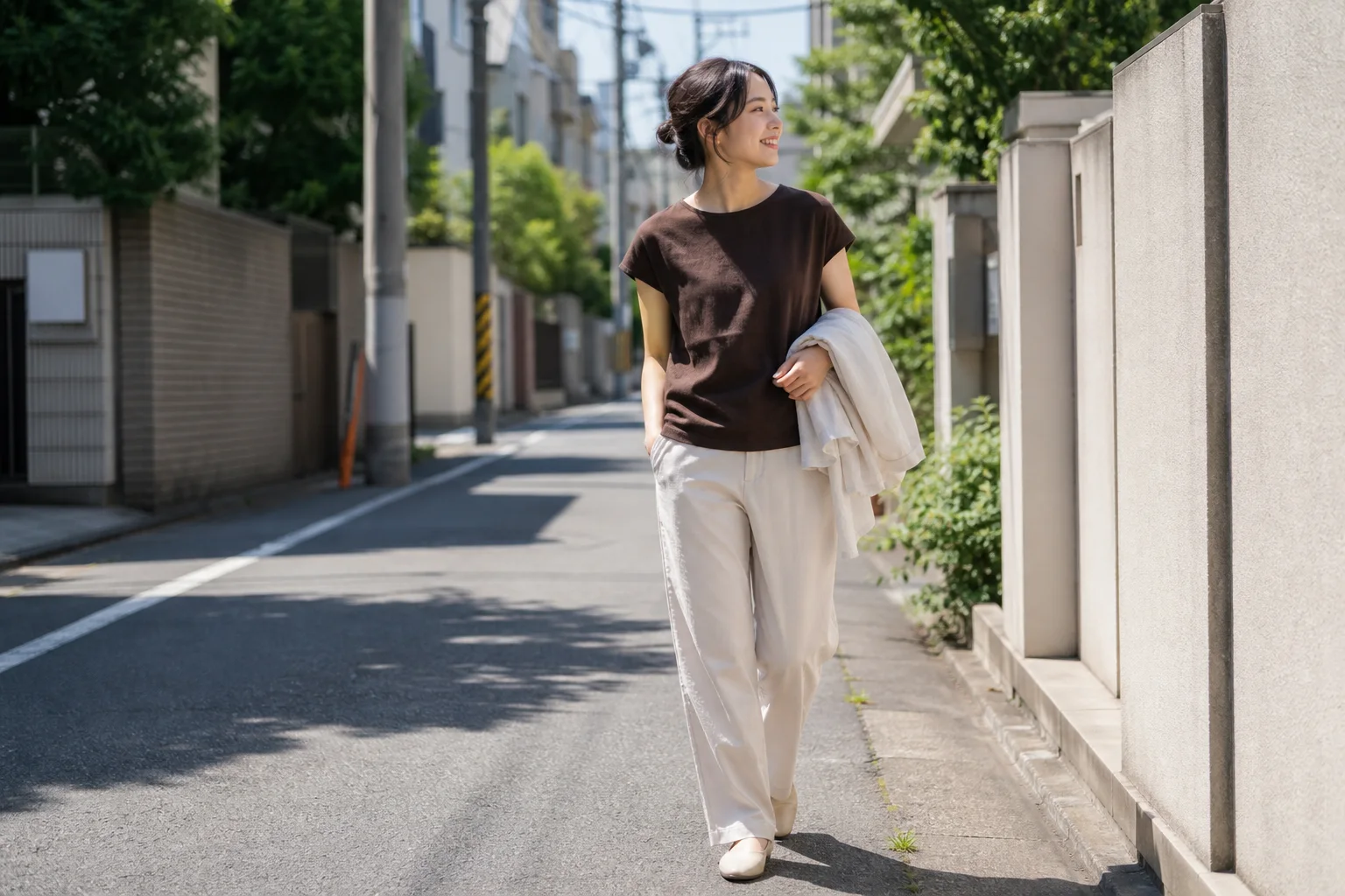 9月の暑い昼、濃いブラウンの半袖トップスと明るいパンツを着て、薄手シャツを腕に持つ若い成人女性のAI生成画像。